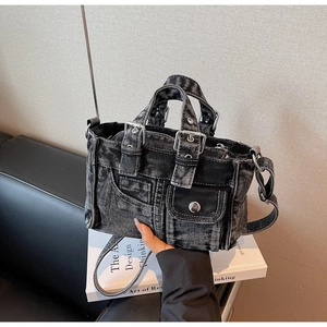 Detail of vintage washed black denim handbag with metallic buckles and rivets