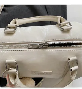 Close-up of a silver smooth zipper and marble texture on white crossbody boston bag