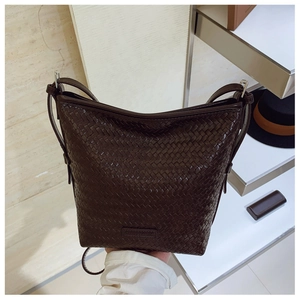 Detail of dark brown woven texture and brand plaque on a stylish bucket bag