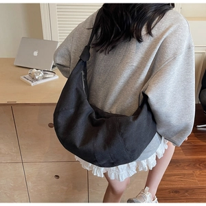 Detail of black canvas dumpling crossbody bag with pleated texture on a model