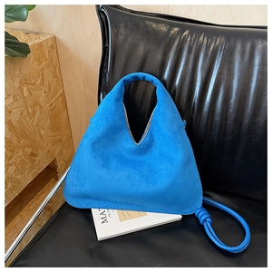Close-up of royal blue suede dumpling bag with soft texture and knotted strap details