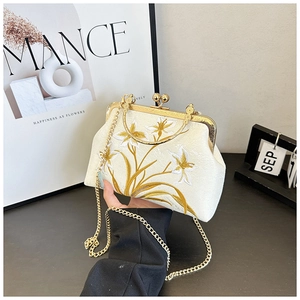 Detail of vintage floral embroidery on off-white fabric bag with gold metal clasp