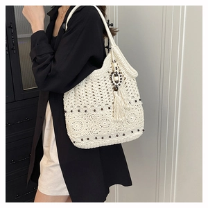 Detailed close-up of handmade cream crochet tote bag with boho tassel charm on model