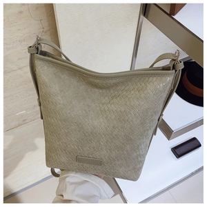 Detail of dark green woven leather texture on a bucket bag with brand label