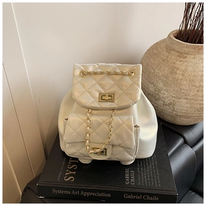 Detail of white quilted mini backpack featuring gold twist-lock chain pockets and drawstring