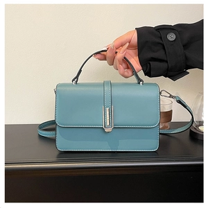 Detailed view of teal textured leather handbag featuring silver metal lock and top handle