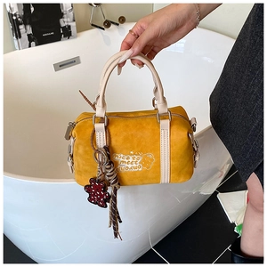 Detail der gelben Boston-Tasche mit Bären-Grafik, beige Griffen und rotem Herz-Anhänger