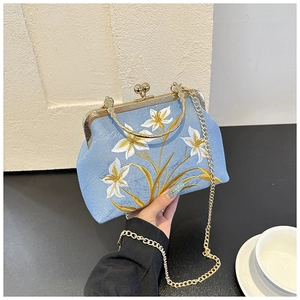 Detailed close-up of light blue cheongsam bag with elegant white lily embroidery and gold chain