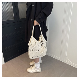 Detail of hand-woven crochet tote bag with bohemian tassels and decorative black beads