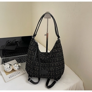 Detailed close-up of black and gold tweed hobo bag showing woven texture and leather straps