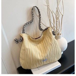 Détail d'un sac cabas beige matelassé avec une anse en corde rayée et étiquette de marque