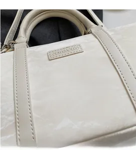 Detail showing the creamy white wrinkled leather texture and precise stitched logo