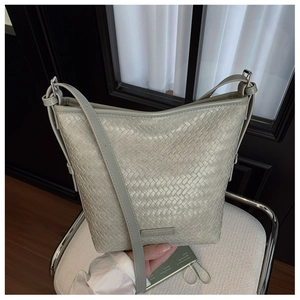 Close-up of a light grey woven leather bucket bag featuring a refined braided texture
