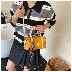 Detail of yellow crossbody bag with soft suede texture and stylish hanging charm