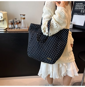 Detail der schwarzen Segeltuchtasche mit weißen Punkten und geräumigem Innenfach