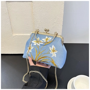 Detail of light blue embroidered handbag with floral patterns and gold chain strap