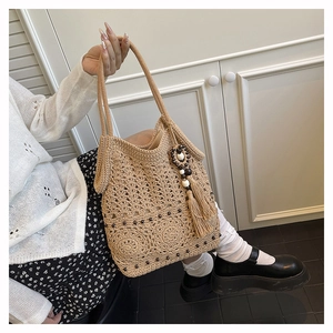 Detailed macro of handwoven cream crochet tote bag with floral patterns and boho tassel