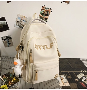 Detail of beige nylon backpack with multiple zippers and a cute white duck pendant charm