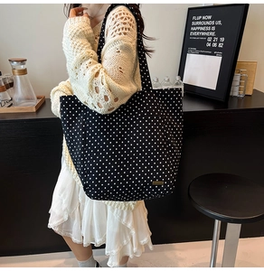 Detailansicht der großen schwarzen Polka-Dot-Einkaufstasche mit Metalletikett und Trägern