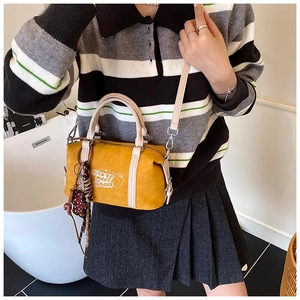 Details der gelben Boston-Tasche mit Schriftzug und Leoparden-Bär-Anhänger