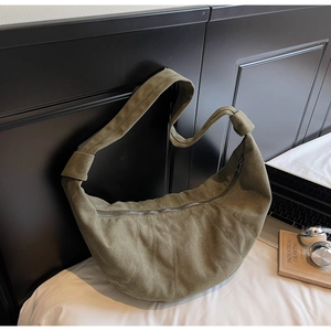 Detailed view of dark green suede croissant bag with stitched pleats and metal zipper