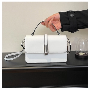 Close-up of a white leather square handbag with a silver metal lock and top handle