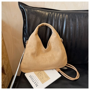 Detailed macro view of khaki suede leather texture and curved handle on hobo bag
