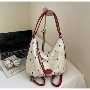 Detail of canvas tote with red bow prints, leather straps and silver metal hardware