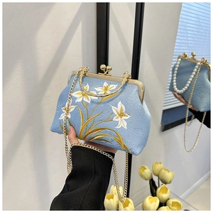 Detailed view of light blue cheongsam bag with elegant floral embroidery and gold chain
