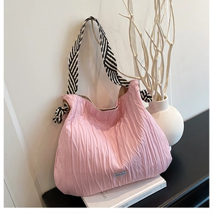 Détail du sac fourre-tout plissé rose avec bandoulière rayée et logo métallique