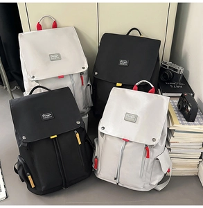 Detail of high-capacity canvas backpacks featuring flap-top design and colorful zipper tabs