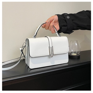 Detailed view of a white leather crossbody bag featuring silver hardware and top handle