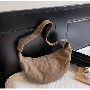 Macro detail of brown suede croissant bag showing stitching texture and zipper closure