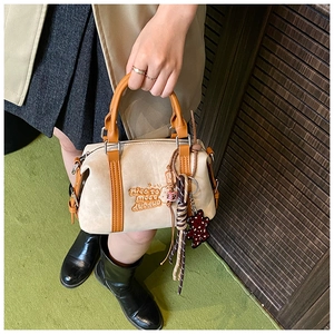 Detail of cream and brown crossbody bag with colorful cords and leopard bear charm