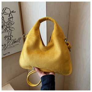 Detail of yellow suede dumpling bag showing knot decor and matte leather texture