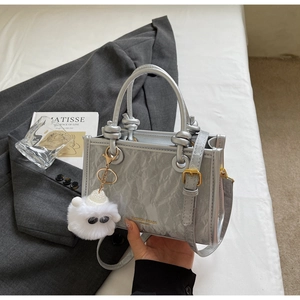 Detail of silver metallic pleated bucket bag with gold lettering and plush lamb charm