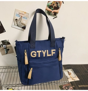 Deep blue nylon backpack detail showing GTYLF letter patch and multiple zipper pockets