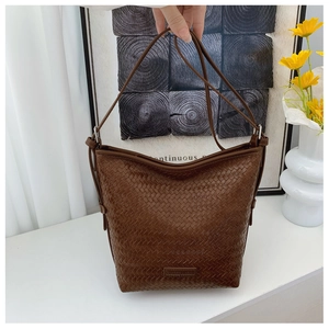 Detail view of deep brown woven leather shoulder bag with embossed logo and elegant strap