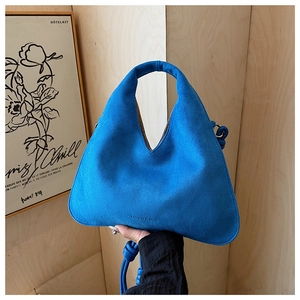 Detail of royal blue suede dumpling bag with fashion text and knotted shoulder strap