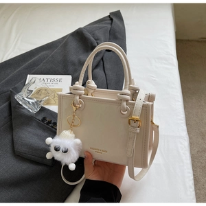 Detail of cream white leather bucket bag with knot handle and plush monster charm