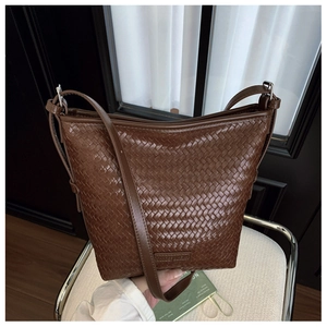 Detail of dark brown woven leather bucket bag texture and embossed logo on a chair