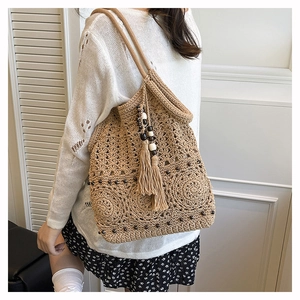Detail of bohemian hand-woven tote bag showing tassel fringe and beaded charm detail