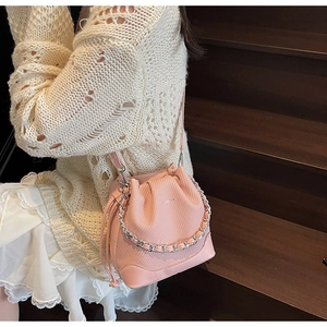 Detailed view of a pink drawstring bucket bag with silver chain and leather texture