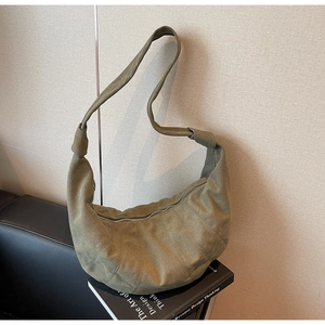 Macro shot of olive green suede crescent bag showing silver zipper and matte texture