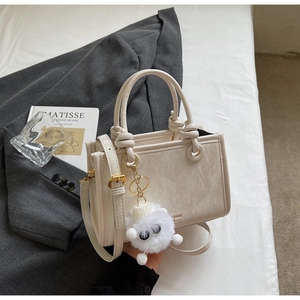 Detail of cream-white leather handbag with marble texture and knot handle design