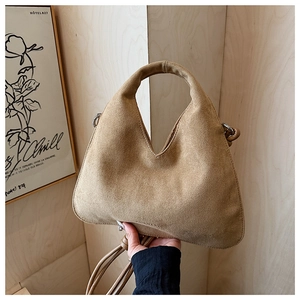 Close-up of camel suede hobo bag with textured finish and elegant triangle design