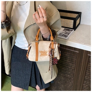 Detail der Boston Bag aus cremefarbenem Stoff mit braunem Besatz und Bärchen-Anhänger
