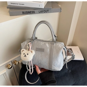 Detail of silver metallic textured pillow bag with wrinkled finish and plush bear charm