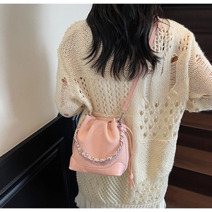 Detail of pink bucket bag with cross-grain texture, silver chain, and drawstring closure