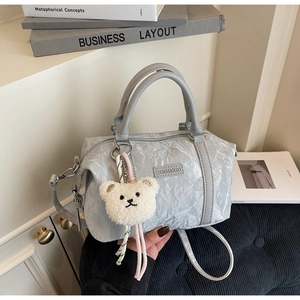 Detail of light blue pleated Boston bag with soft texture and cute bear pendant